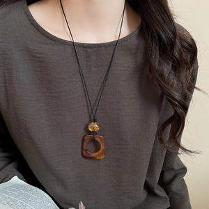 Close-up of amber resin square pendant necklace with black cord on a professional model