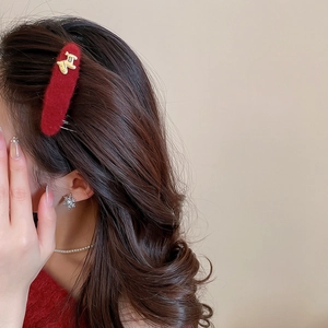 Detail of red flocked hair clip with gold dog charm, snowflake earring and pearl necklace
