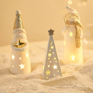 Glow ceramic Christmas Santa and tree decorations with warm LED lights on snow background