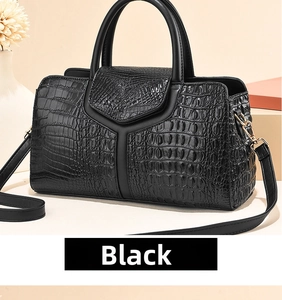 Close-up of black crocodile embossed boston bag with golden hardware and leather strap