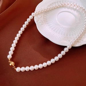 Detailed macro view of white pearl necklace with golden magnetic clasp on velvet