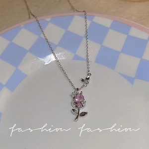 Pink tulip zircon necklace with silver butterfly pendant on a decorative ceramic plate