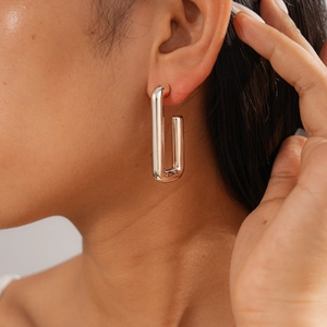Close-up of minimalist silver rectangular earrings worn to show modern geometric design