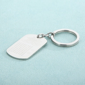 Stainless steel lotus keychain with engraved Chinese poem on a textured teal background