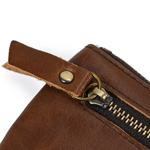 Close-up of brown genuine leather texture and durable metal YKK zipper with rivet puller