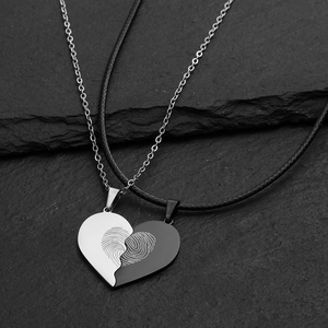 Detail of interlocking heart pendants with fingerprint engraving on black stone background