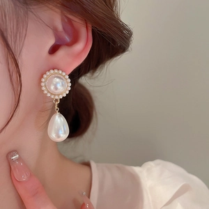 Dettaglio di eleganti orecchini di perle con design vintage indossati da una modella