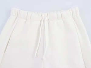Close-up of white knitted sweatpants featuring elastic waistband and adjustable drawstring
