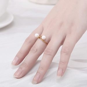 Close-up of 18K gold plated double pearl crossover open ring on model with silk backdrop