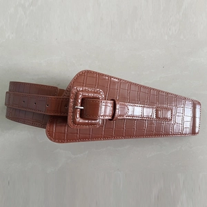Detail of brown wide elastic corset belt with crocodile skin texture and rectangular buckle