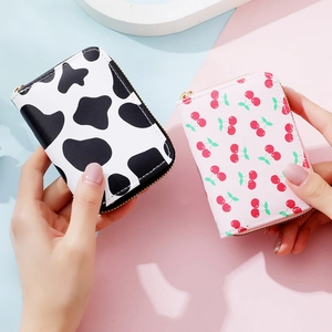 Slim accordion card holders with cow print and cherry patterns and gold zippers