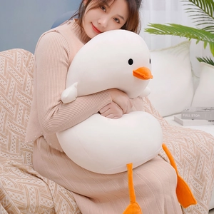Detail of soft white duck plush pillow with orange beak shown in a home setting