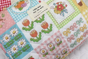 Close-up of quilted floral cosmetic bag with textured fabric and vintage cloth label