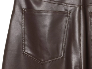 Dettaglio dei pantaloni in ecopelle marrone scuro con cuciture sulla tasca