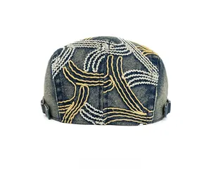 Detailed back view of washed denim beret featuring yellow contrast stitching and metal buckle