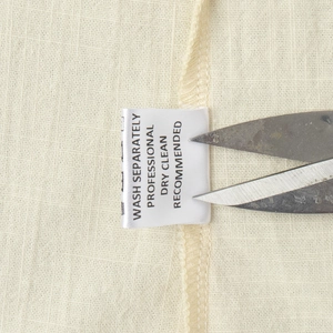 Detail of the washing label on light beige sleeveless dress with care instructions