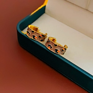 Detail of vintage gold plated C-shape earrings with brown leopard enamel pattern