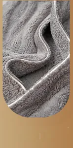 Close-up of thick grey plush fabric showing soft texture and premium white piping detail