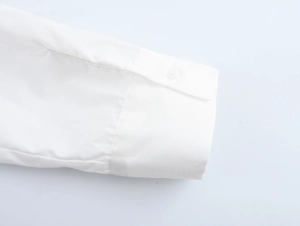 Close-up of white vacation set shirt cuff with fabric texture and button detail