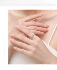 Close-up of sparkling marquise-cut floral ring on hand in soft warm aesthetic lighting