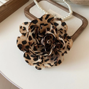 Detail of leopard print fabric flower clip with layered petals on a wooden tray
