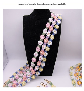 Macro detail of hand-woven floral shoulder strap with colorful cotton petals and gold hooks