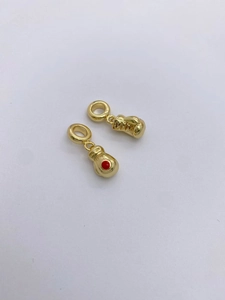 Macro detail of gold-plated boxing glove pendants with red cubic zirconia accents