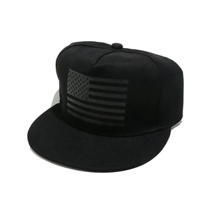 Close-up of a black snapback cap featuring a monochrome American flag print and flat brim