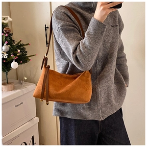 Detail of the brown suede crossbody bag showing the soft matte texture and decorative ribbons