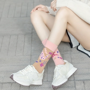 Detail of pink and brown asymmetric socks featuring cat and botanical knit patterns