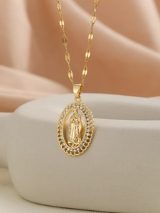 Close-up of golden Virgin Mary pendant with white cubic zirconia inlay on soft fabric