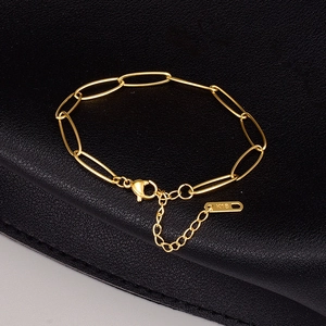 Elegantes 18K vergoldetes Büroklammer-Armband aus Titanstahl auf schwarzem Lederhintergrund