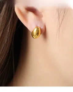 Close-up of golden teardrop stud earrings with a polished mirror finish on model