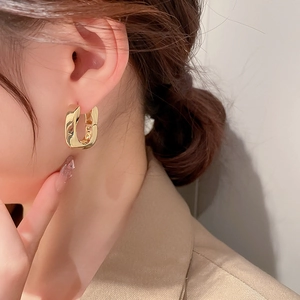 Gros plan d'élégantes boucles d'oreilles dorées torsadées en U portées par un mannequin