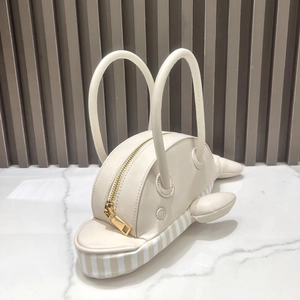 Detail view of cream dolphin shaped handbag with golden zipper and striped base