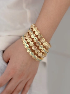 Close-up of golden smiley face bracelets with colorful crystal eyes on model wrist