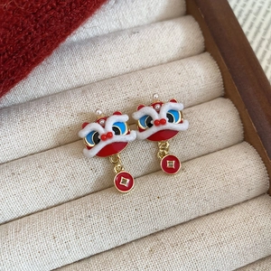 Detail of red lion dance earrings with copper coin pendants on velvet display