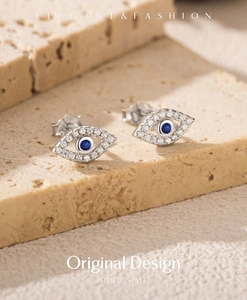 Detailed close-up of S925 silver evil eye stud earrings with blue gems and small diamonds