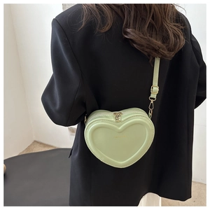Detail of mint green heart-shaped crossbody bag with gold zippers and fashion text