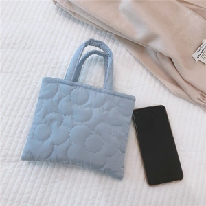 Dettaglio della mini borsa trapuntata azzurra con ricami floreali e manici superiori