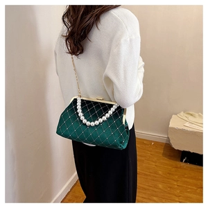 Detail of dark green velvet shell bag with quilted texture and elegant pearl handle