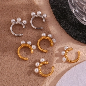 Detail of 18K gold and silver plated ear cuffs with small faux pearls on brown felt