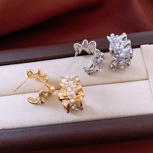 Detail of C-shaped pleated earrings with white pearls and small diamonds in jewelry box