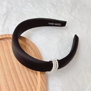 Close-up of handmade black satin headband featuring triple-row pearl embellishments