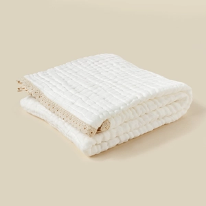 Close-up of 6-layer white muslin baby blanket with delicate beige lace trim texture