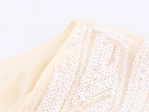 Close-up of white sequins sewn on beige mesh fabric for elegant evening dress