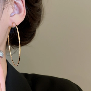 Gros plan d'une grande créole dorée avec texture martelée sur l'oreille d'un mannequin