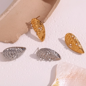 Détail macro de boucles d'oreilles coquillages dorées et argentées avec perles et eau