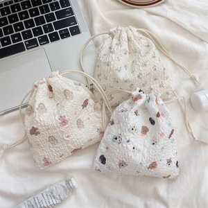 Detail of drawstring pouches in seersucker fabric with floral and cartoon bear patterns
