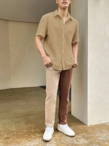 Full body view of men's khaki waffle textured short sleeve shirt with neutral trousers